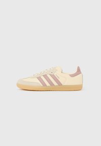 Superge Samba iz kremnega usnja z bledo roza črtami, okroglim prstom, teksturirano podplatom in oblazinjenimi poudarki na peti. Podplat iz gumenega materiala barve gume.