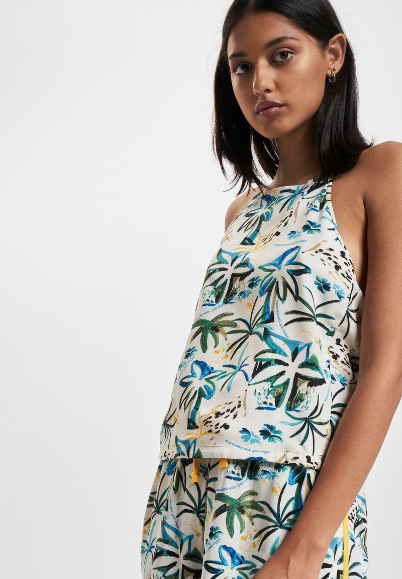 Blusa sin mangas de tejido ligero con estampado de hojas de palma multicolores sobre un fondo crema; incluye acentos amarillos y un corte relajado.