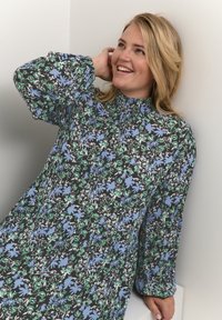 Vestido de manga larga con fondo negro y patrones florales en azul y verde. Tejido ligero con cuello alto y detalles fruncidos.