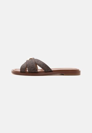 Sandale plate marron à enfiler avec des brides croisées texturées et un petit talon sur fond blanc.