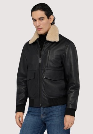 Schwarze Lederbomberjacke mit beigem Pelzkragen, zwei vorderen Taschen, gerippten Bündchen und einem Reißverschluss. Die strukturierte Oberfläche verleiht Tiefe.