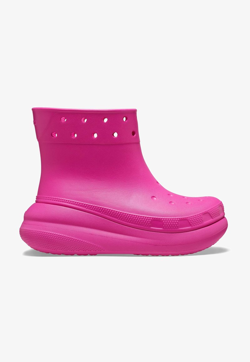 Botín rosa a la altura del tobillo, hecho de goma suave, con orificios de ventilación y una suela texturizada para mayor agarre. Punta redondeada y talón acolchado.