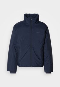 Marineblauwe gewatteerde pufferjas met hoge kraag en volledige ritssluiting. Heeft ritssluitingen aan de zijkanten en ribgebreide manchetten voor extra warmte.