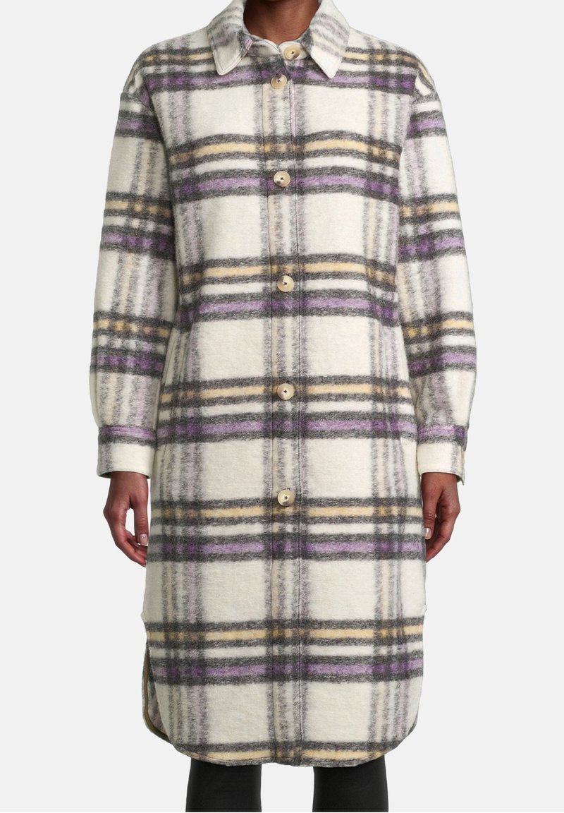 Abrigo largo de lana de cuadros con cierre de botones en tonos de crema, púrpura, gris y beige, llevado sobre pantalones negros.