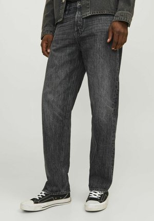 Jean en denim noir avec une coupe droite, featuring un délavage clair et des détails de couture subtils, associés à des baskets noir et blanc.