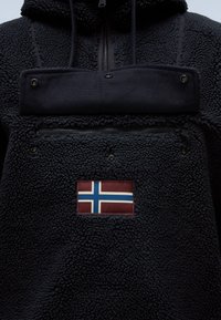 Sudadera de forro polar negra con un bolsillo con cremallera, que presenta un parche de la bandera noruega. Tejido con textura y cálido; capucha ajustable con cordones.