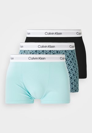 Tři páry pánských boxerů Calvin Klein: jedny v jednobarevné černé, jedny světle modré a jedny s geometrickým vzorem v modrozelené a černé, každé s bílým pasem.