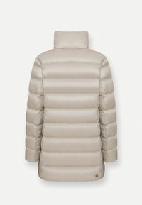 Chaqueta acolchada beige con textura de acolchado vertical, un cuello alto y un dobladillo ligeramente curvado. Presenta un pequeño logo en la parte inferior izquierda.