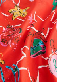 Czerwony materiał z różnymi ozdobnymi ozdobami świątecznymi w żywych kolorach, w tym gwiazdy, dzwonki i bombki, z wyraźnymi konturami i wzorami.