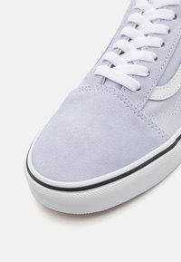 Lilac suede sneaker with white laces, black rubber sole, and signature white accents along the side. Textured toe and smooth panels.