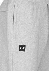 Grijze sweatpants van zachte stof, met zijzakken en een zwart Under Armour-logo aan de linkerkant. Elastische tailleband voor comfort.