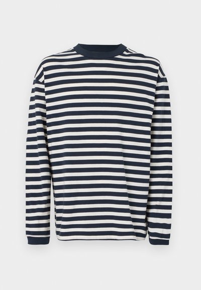 Πουκάμισο με μακριά μανίκια, με οριζόντιες ρίγες σε ναυτικό μπλε και λευκό, λαιμόκοψη τύπου crew και ριμπ μανσέτες πάνω σε λευκό απλό φόντο.