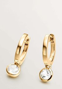 Pendientes de aro de oro con un acabado pulido, que cuentan con un colgante de cristal transparente en la parte inferior. Diseño sencillo, con una textura suave y forma circular.