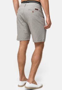 Gråstribede shorts med en afslappet pasform, der har en sort elastisk talje og brune læderdetaljer. Enkle baglommer med knapdetalje.