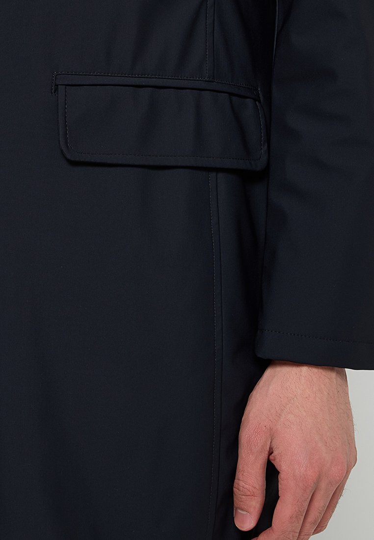 Marineblaue wasserdichte Jacke mit strukturierter Oberfläche, ausgestattet mit einer Klapptasche auf der linken Seite, nahtlosem Nähten und geradem Schnitt.