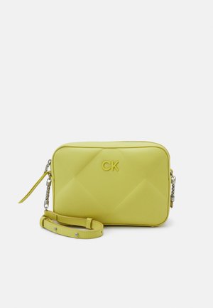 Borsa a tracolla sintetica gialla trapuntata con tracolla removibile, caratterizzata da un logo "CK" tono su tono e dettagli in metallo argento. Texture liscia.