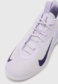 Light purple Nike sneakers with a textured upper, flat laces, and a curved silhouette. Features a dark purple swoosh and cushioned collar.