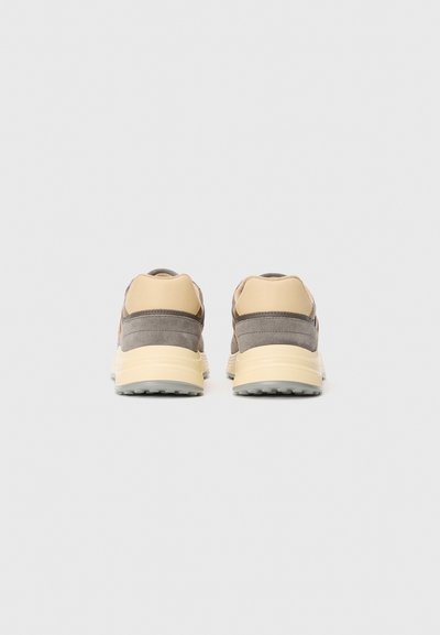 Pair of beige and gray sneakers viewed from the back with thick cream-colored soles on a plain white background.