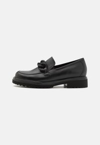Mocasines de piel negra con un nudo decorativo en la parte delantera, con una suela texturizada y un tacón bajo. Superficie suave y diseño clásico.