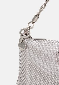 Pochette à perles argentées avec une surface texturée, une bandoulière en chaîne argentée et un charme logo. Présente une forme arrondie et une brillance sur le matériau.