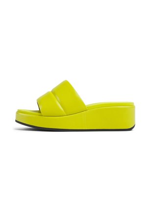 Chanclas amarillas brillantes con tiras gruesas y acolchadas, textura suave y suela de plataforma gruesa, con un fondo negro que proporciona contraste.