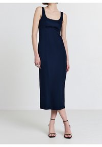 Robe midi bleu marine avec un décolleté carré, une silhouette ajustée et des bretelles spaghetti. Texture lisse avec un minimum de détails de couture.