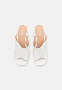 Sandali bianchi senza cinturino con fasce incrociate, design con punta aperta e finitura liscia. Soletta color beige chiaro con nome del marchio impresso.