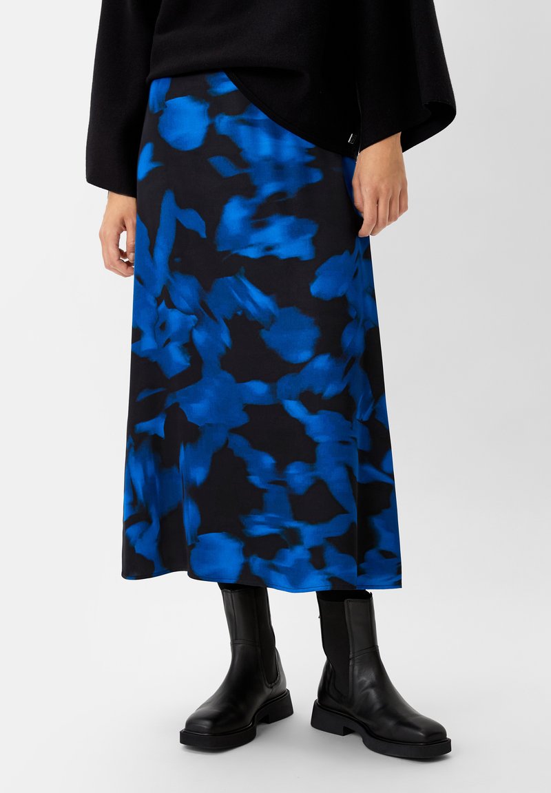 Long black skirt with blue abstract pattern. Made from a smooth fabric, it features a flared design and is paired with black ankle boots.