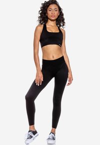 Set di reggiseno sportivo e leggings neri realizzato in un tessuto morbido ed elastico, con scollatura quadrata, vita alta e design elegante.