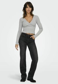Grijze geribbelde langemouwtop met een V-hals, cropped zoom en gerimpelde randen, gecombineerd met zwarte rechte jeans en enkellaarzen.