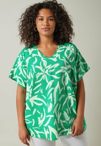 Camiseta verde de cuello en V, hecha de tela ligera, con un patrón abstracto de hojas blancas, mangas cortas y un corte relajado.