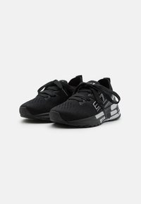 Scarpe da ginnastica nere con una tomaia in rete texturizzata, lacci piatti e una suola ammortizzata con un dettaglio a striscia bianca sul lato.