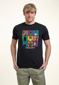Black t-shirt featuring a colorful Minecraft graphic with various characters in squares. Short sleeves, crew neck, cotton material.