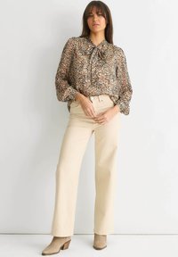 Leopard print blouse with a tie neck, long sleeves, sheer fabric. Paired with light beige high-waisted pants and taupe ankle boots.