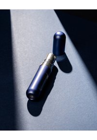 Marineblå metal sprayflaske med sølvdyse og låg, cylindrisk form, glat tekstur og et gennemsigtigt kiggefelt.