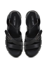Sandales en cuir noir avec croix de brides, boucle en métal ajustable et semelle texturée. Conception à dos ouvert avec doublure intérieure lisse.
