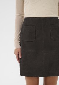 Donkergrijze suède rok met twee voorzakken en een rechte snit. Het materiaal heeft een soepele textuur met een matte afwerking.