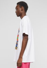Hvid bomulds T-shirt med et farverigt grafisk print af tegneseriefigurer på forsiden, løs pasform med korte ærmer.