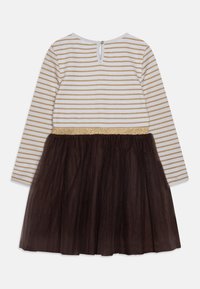 Vit långärmad topp med guld horisontella ränder, guld midjeband och mörkbrun tyllkjol fäst, klänningen sedd bakifrån.