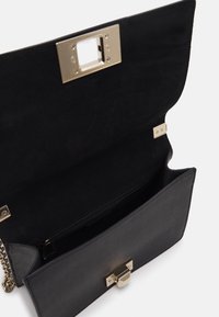 Black handbag with a gold clasp, partially open to reveal a smooth interior. Contains a zipped compartment and textured lining.