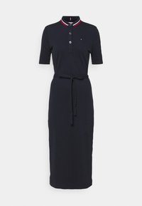 Navy Polokleid mit kurzen Ärmeln, fünf Knöpfen und kontrastierendem rot-weißen Kragen. Hat einen Taillengürtel für zusätzliche Form.