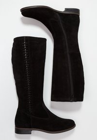 Botas de ante negras hasta la rodilla con cremallera lateral, panel elástico y detalle trenzado a lo largo de la costura exterior. Suela plana y diseño de punta redondeada.