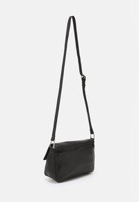 Czarna prostokątna skórzana torba na ramię z regulowanym paskiem i przednią kieszenią na zamek, na jasnym, jednolitym tle.