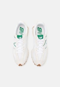 Białe sportowe sneakersy z zielonymi akcentami, wierzch z zamszu i siateczki, wyraźne sznurowadła, teksturowana gumowa podeszwa oraz wyraźne logo na wkładce.