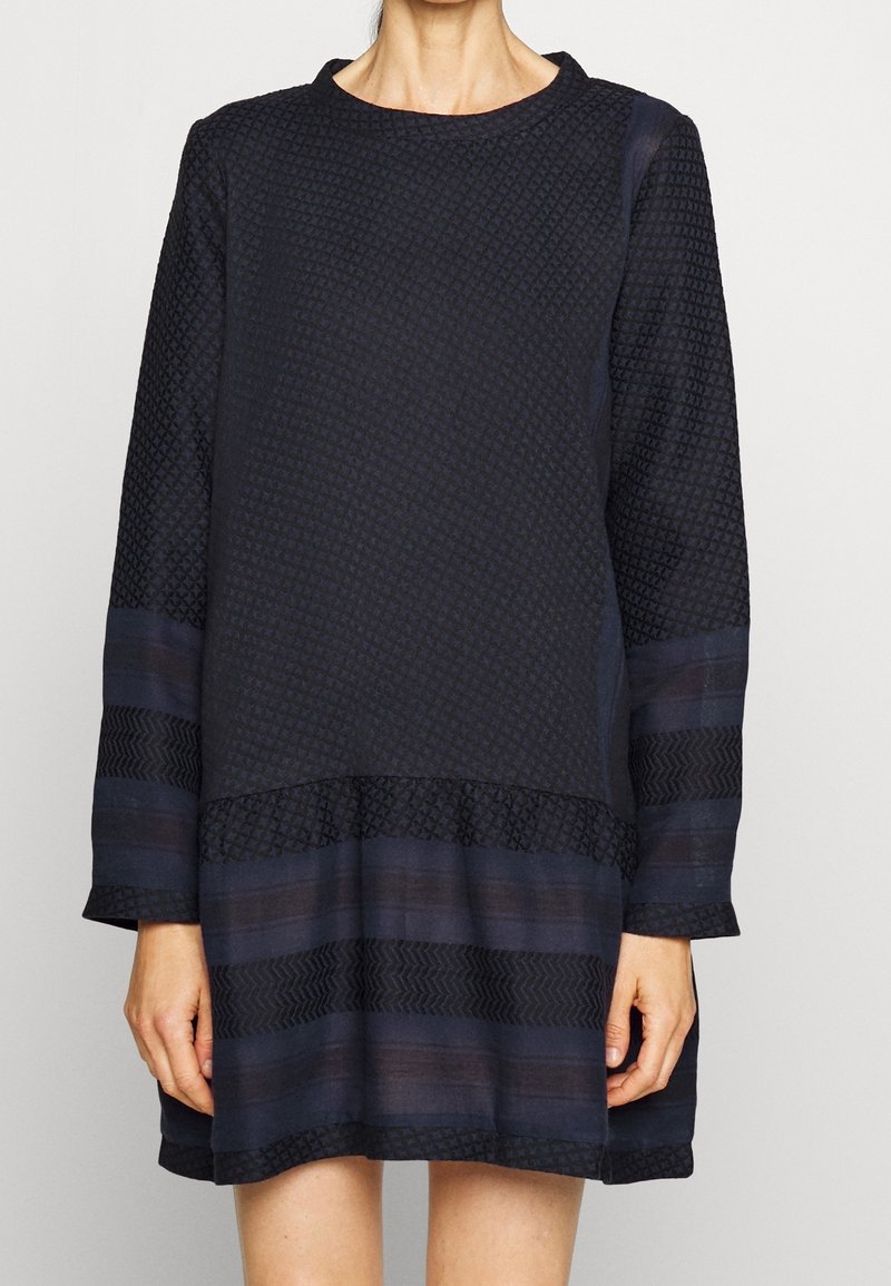 Marineblaues Langarmkleid aus strukturiertem Stoff, mit gemustertem Oberteil und geschichtetem Saumdesign. Einfacher runder Ausschnitt und lockere Passform.