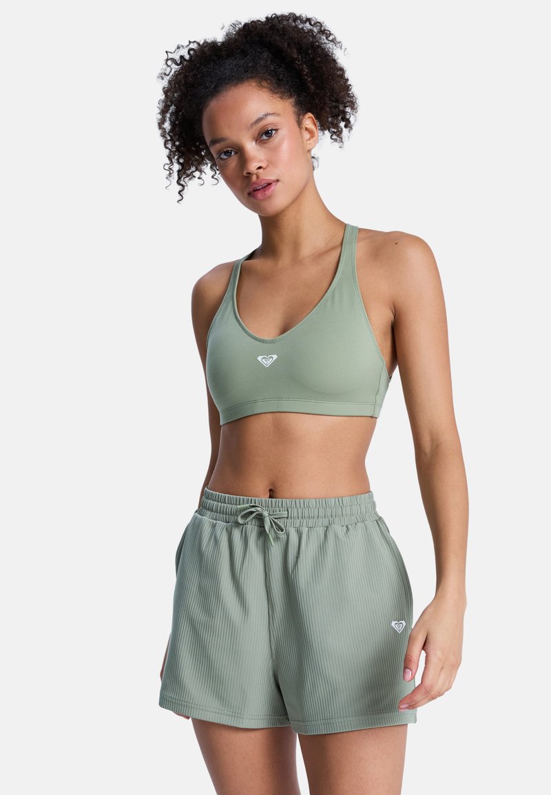 Bralette verde deportivo y shorts a juego hechos de tela acanalada, con un logo en el bralette y una cintura elástica en los shorts.
