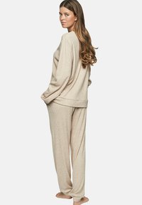 Beige gebreide loungewear set met een relaxte pasvorm, lange mouwen en een wijde pijp, voorzien van ribbeltextuur en zonder zichtbare hardware.