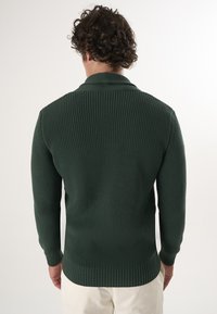 Tume rohelise värvi soonikuga kootud särk, millel on särgikaelus ja pikad varrukad. Nähtavad õmblused ja tihe hem.