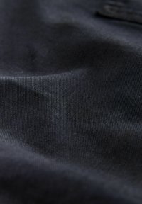 Close-up of textured black fabric with visible fine ribbing and soft folds under diffuse lighting.