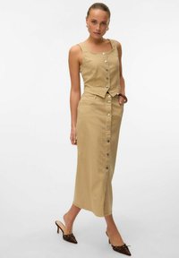 Ensemble deux pièces kaki avec un haut boutonné court et une jupe mi-longue dotée d'une fermeture à boutons à l'avant et de poches. Tissu lisse et texturé.